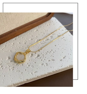 Détail d'un collier en or avec pendentif en nacre blanche sur un support en pierre