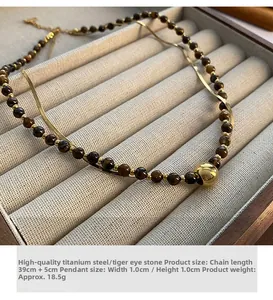 Detail of double-layer necklace with brown tiger eye beads and gold titanium steel ball