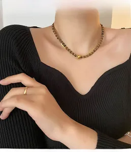 Detail of double-layer tiger eye stone necklace with gold beads on a black sweater