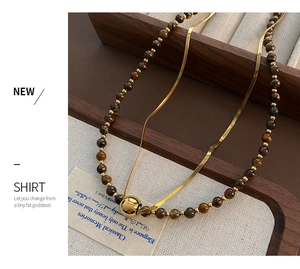 Detailed close-up of a double-layer tiger eye stone necklace with gold metal ball pendant