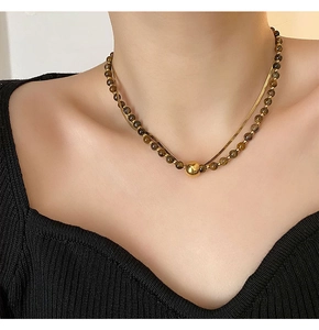 Detail of double-layer necklace with golden snake chain and brown tiger eye beads