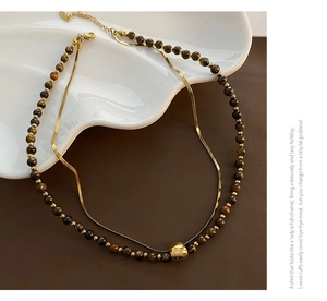Detail of double-layer tiger eye bead necklace with gold snake chain and lobster clasp