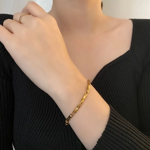 Gold Mobius twisted chain bracelet for men and women shown on model with black outfit