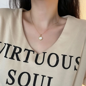 Collier élégant en chaîne dorée avec un pendentif en nacre blanche sur un mannequin