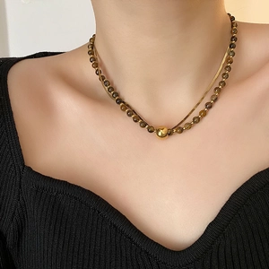 Elegant gold snake chain and brown tiger eye bead layered necklace on black sweater