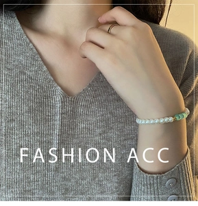 Detailed view of beaded bracelet with pearl beads and green glass on model wrist