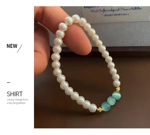 Detailed shot of white pearls bracelet with light blue beads and golden metal spacers