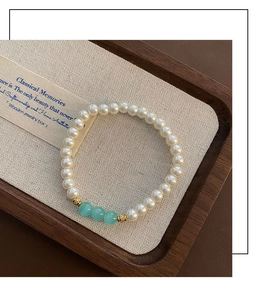 Detail of beaded bracelet featuring white pearls and light blue quartz accent beads