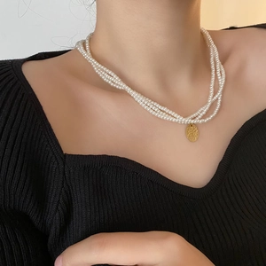 Collana di perle di vetro multistrato francese con ciondolo dorato su modella
