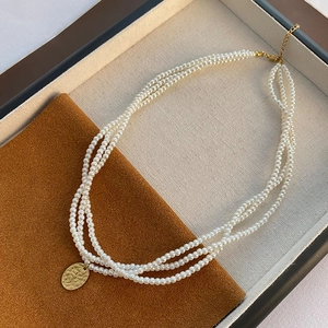 Collana di perle a tre strati con ciondolo ovale dorato strutturato e chiusura a moschettone