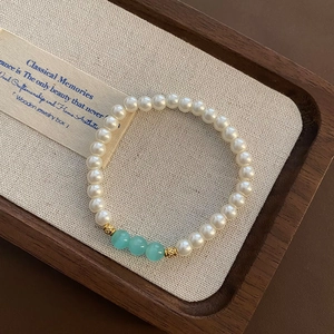 Elegant pearl and green glass bead adjustable stainless steel bracelet on wooden tray