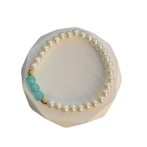 Adjustable titanium steel bracelet with white pearls and blue beads on a geometric stand