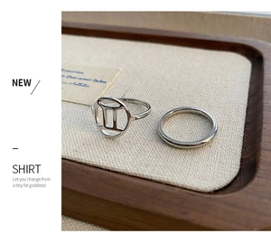 Macro shot of silver titanium Gemini symbol ring set on a rustic wooden jewelry tray