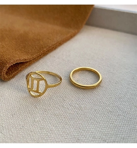 Macro view of gold titanium Gemini zodiac sign signet and minimalist band ring set