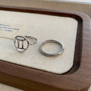 Polished titanium steel Gemini constellation rings set in a wooden display tray