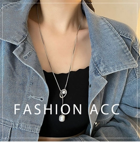 Detail of a fashion pearl pendant necklace with silver chain on model outfit