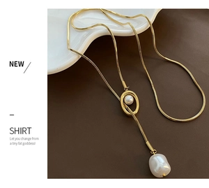 Detail of a gold snake chain necklace featuring a baroque pearl pendant and gold loop