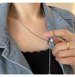 Elegant silver snake chain necklace with pearl pendant worn over a black top