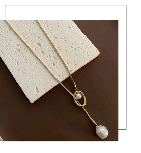 Detail of gold snake chain necklace featuring elegant irregular baroque pearl pendant