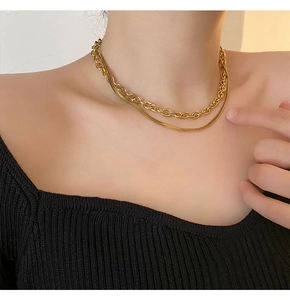 Détail d'un collier double épaisseur doré avec une chaîne à maillons et une chaîne serpent