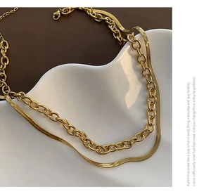 Détail d'un collier superposé doré avec maille serpent et chaîne à gros maillons