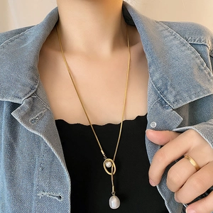 Long gold snake chain necklace featuring elegant pearl pendant on female model
