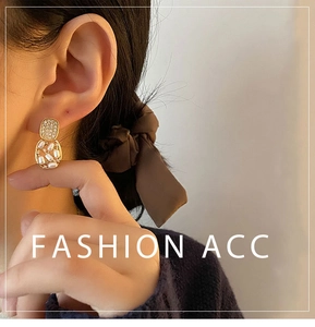 Close-up of vintage gold earrings with shimmering square studs and pearl cage drops