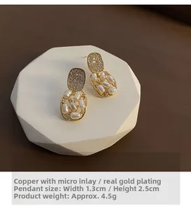 Detailed view of vintage gold-plated earrings with white pearls and micro-pave crystals