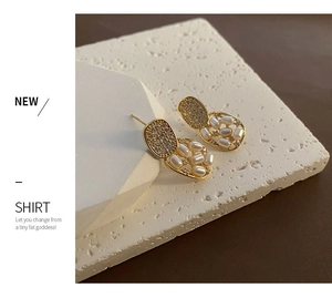 Detail of elegant gold-tone drop earrings with pavé zircons and delicate white pearls
