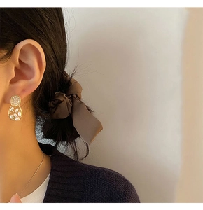 Detailed view of elegant gold geometric earrings with pearls worn by a model