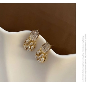 Detail of vintage gold earrings with sparkling rhinestones and elegant white pearls
