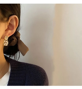 Detail of vintage gold-plated earrings with beige pearls on model against soft background