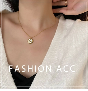 Detail of a 18K gold plated titanium necklace with shell moon pendant on model