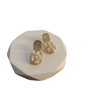 Elegant gold vintage earrings with freshwater pearls on white geometric block
