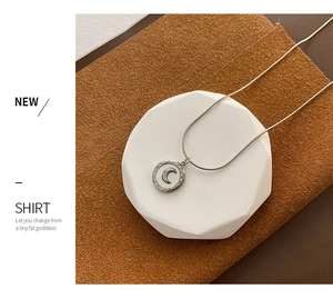Detailed shot of crescent moon pendant with hammered texture and sleek snake chain