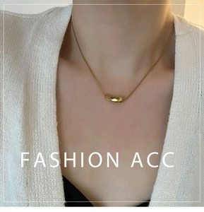 Macro detail of minimalist gold twisted pendant on a fine snake chain necklace