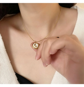Close-up of golden moon pendant with white shell inlay worn on a delicate chain