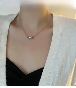 Close-up of minimalist silver irregular pendant with sleek snake chain on model