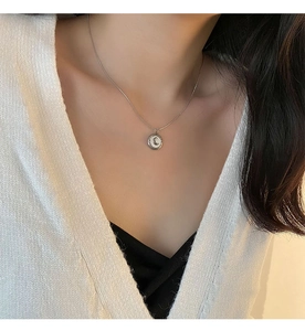 Close-up of crescent moon necklace with white shell pendant on a model's neck