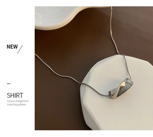 Macro detail of minimalist silver twisted geometric pendant on sleek snake chain