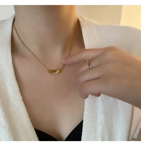 Detail view of 18K gold-plated twisted pendant necklace and matching band ring on model