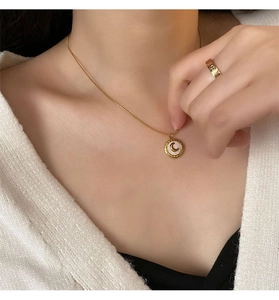 Close-up of golden moon pendant with white shell inlay and hollowed star ring on model