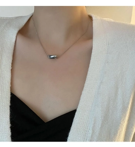 Minimalist silver irregular pill pendant necklace on a model's neck for chic daily wear
