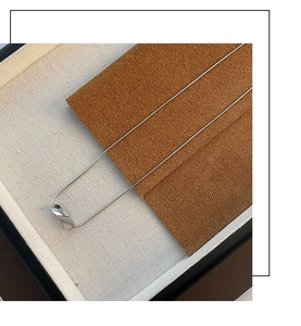 Close-up of polished silver irregular geometric pendant on a minimalist necklace