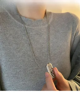 Detail of silver hexagonal tire pattern pendant on long chain worn over grey sweater