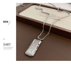 Detailed view of silver rectangular pendant with textured geometric grooves and box chain