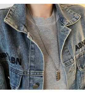 Detail of a rectangular silver pendant with chain texture on a long beaded necklace