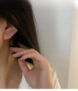 Close-up of minimalist sterling silver ball earrings worn in two lobe piercings