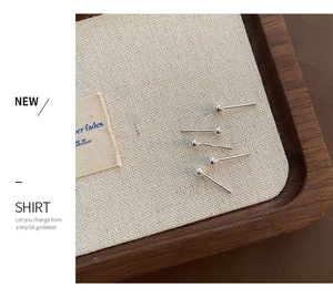 Set of five polished sterling silver ball stud earrings displayed on a rustic linen tray