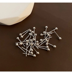 Macro view of polished silver bead earrings on dark textured leather background